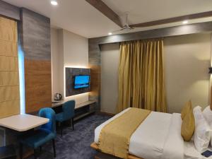 瓦拉纳西PRIME LAND的酒店客房设有一张床、一张书桌和一台电视机。