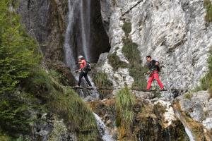 FiavèAlbergo Genzianella的三人在瀑布前穿过绳桥