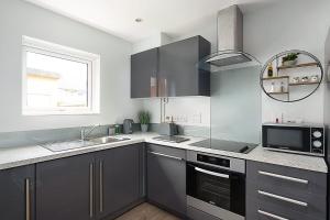 雷丁Stylish Serviced Apartment in Reading的厨房配有灰色橱柜、水槽和窗户。