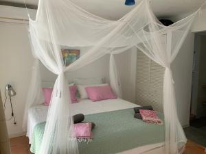 威利布罗德Villa 13, Coral Estate的卧室配有带粉红色枕头的天蓬床