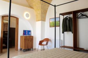 Caprarica di LecceMasseria Rifisa AgriResort的一间卧室配有一张床、一把椅子和镜子