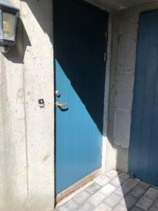 卑尔根Koselig nyoppusset 3 roms leilighet med egen parkeringsplass i rolige omgivelse nær sjøen, 2 mil nord for Bergen sentrum.的建筑物一侧的蓝色门