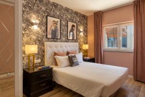 波尔蒂芒梅德旅馆的卧室配有白色的床和一张带照片的墙壁