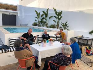 奥良Casa Rosa Villa with Pool in Olhao Centre的一群人坐在桌子旁,听着音乐