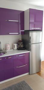 萨格勒布Apartman Aura的厨房配有紫色橱柜和不锈钢冰箱