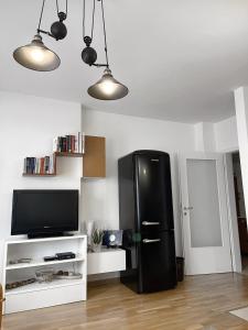 普里什蒂纳Pristina City Apartment的客厅设有一台黑色冰箱,配有电视