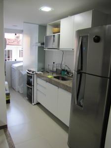 马塞约Moderno apartamento perto da praia的厨房配有白色橱柜和不锈钢冰箱