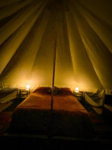 加伯维尔Glamping in the Redwoods的帐篷内的一张床位,上面有两盏灯
