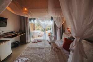 皮帕Xamã Senses - Hotel Pousada的一间卧室配有一张带窗帘的床和浴缸