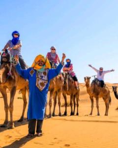 梅尔祖卡Overnight Desert Camp的一群人骑着骆驼