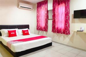 瓜埠OYO 90324 Muar Station Hotel的一间卧室配有一张带红色枕头和粉红色窗帘的床