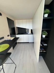 劳特阿赫KODA LOFT - Urlaub im Tiny House Bodensee的客房设有书桌和带白色橱柜的厨房。