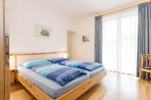 卡尔达罗Appartement Florian的一间卧室配有一张带蓝色床单的床和一扇窗户。
