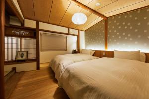 京都Gion Shirakawa no Yado by YADORU KYOTO HANARE的一间卧室设有两张床和窗户。