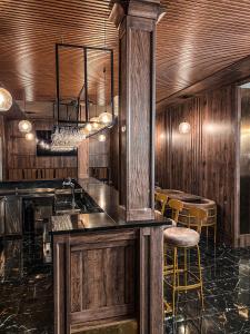 赫拉布斯Hotel Petra的一间带木墙的厨房和一间带凳子的酒吧