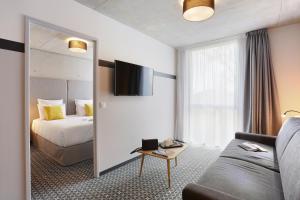 布拉尼亚克Odalys City Toulouse Blagnac Aéroport的酒店客房配有床、沙发和镜子