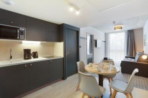 布拉尼亚克Odalys City Toulouse Blagnac Aéroport的厨房以及带桌椅的起居室。