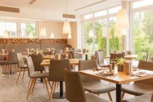 莱茵河畔因格尔海姆瓦塞韦恩酒店的餐厅设有木桌、椅子和窗户。