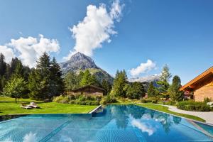 莱赫阿尔贝格Post Lech Arlberg的一座位于花园内的游泳池,花园内有山地背景