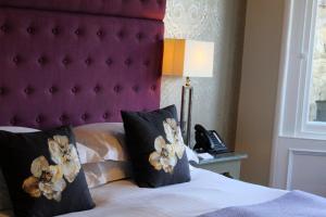 爱丁堡24号皇家露台酒店的一间卧室配有一张带紫色床头板的床和一部电话