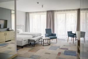 什切尔克Magnus Resort的酒店客房配有床、椅子和电视。