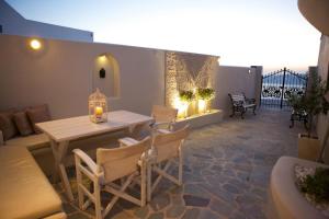 菲罗斯特法尼Sunset View Villa Santorini - with Outdoor Jacuzzi的天井配有桌椅和沙发。