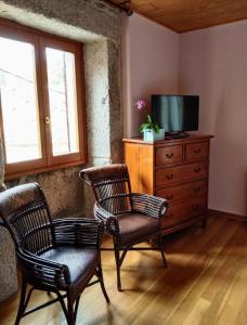 洛维奥斯Casa Rosalia的客厅配有两把椅子和带电视的梳妆台。