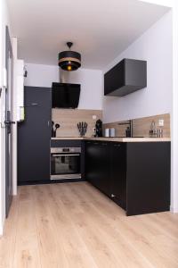 拉弗雷切Appartement 70m2 hyper centre avec baignoire balnéo的厨房配有黑色橱柜和木地板