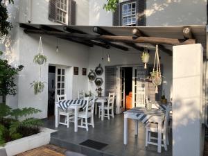 比勒陀利亚Battiss Guest House的庭院配有白色的椅子、桌子和桌椅。