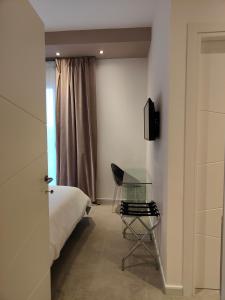马达莱纳Capricci di Vento - Design Guest House的一间卧室配有一张床、一把椅子和一张玻璃桌