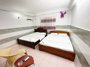 胡志明市Huy Hoàng Hotel的一间设有两张床和椅子的房间