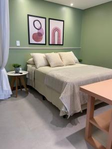 拉古纳Residence Farol - Loft 206的绿色卧室,配有床和两张桌子