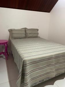 巴纳内拉斯Chalé Serrano的一张带条纹毯子和粉红色凳子的床
