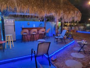 Greenacres CitySusan and Ledif's Tropical Hideaway的酒吧在晚上在甲板上摆放着凳子和椅子