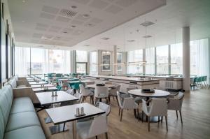 加勒穆恩Radisson RED, Oslo Airport的餐厅设有桌椅和大窗户。