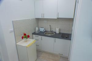 蒂瓦特Apartments KOVAC的厨房配有白色橱柜、水槽和鲜花