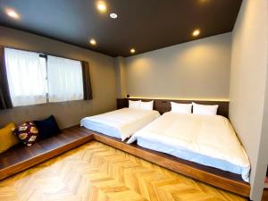 福冈TABISAI HOTEL Terrace 博多的铺有木地板的客房内的两张床
