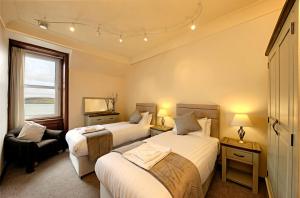 奥本Argyll Mansions的一间卧室设有两张床、一把椅子和一个窗户。