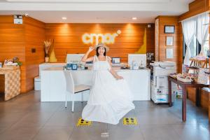 清迈Cmor by Recall Hotels SHA Extra Plus的站在柜台前身穿白色衣服的女人
