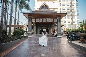 清迈Cmor by Recall Hotels SHA Extra Plus的站在建筑物前身穿白色衣服的女人