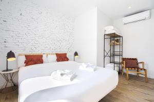 马德里Vallecano Apartments by Olala Homes的一间白色卧室,配有两张床和砖墙