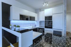 贝尔格莱德Pleasure Lux1 Apartment的厨房配有白色橱柜和黑色地板