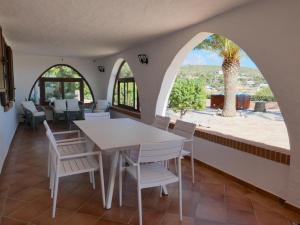 MaladrosciaAppartamento in villa panoramica Maladroxia的一间设有桌椅和棕榈树的用餐室