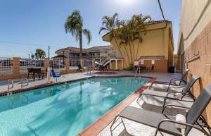 长滩Quality Inn Long Beach - Signal Hill的一座带椅子的游泳池以及一座建筑