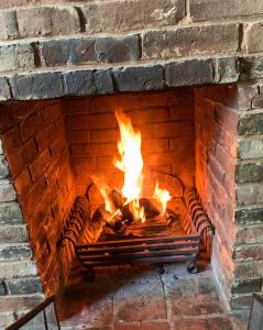 QuorndonStoop Cottage - in the heart of Quorn的砖砌壁炉,壁炉里放着火