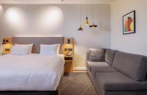 沃尔堡Holiday Inn The Hague - Voorburg, an IHG Hotel的一间卧室配有一张床和一张沙发