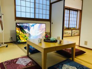 东京Green House 101的客厅配有桌子和大屏幕电视