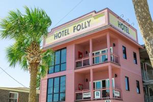 富丽海滩Hotel Folly with Marsh and Sunset Views的粉红色的酒店,前面有棕榈树