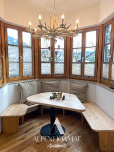 加尔米施-帕滕基兴Alpenhoamat Apartments的客房设有桌子、长凳和窗户。