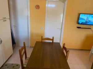 里贝拉Accogliente Appartamento Costa Makauda的用餐室配有木桌和平面电视。